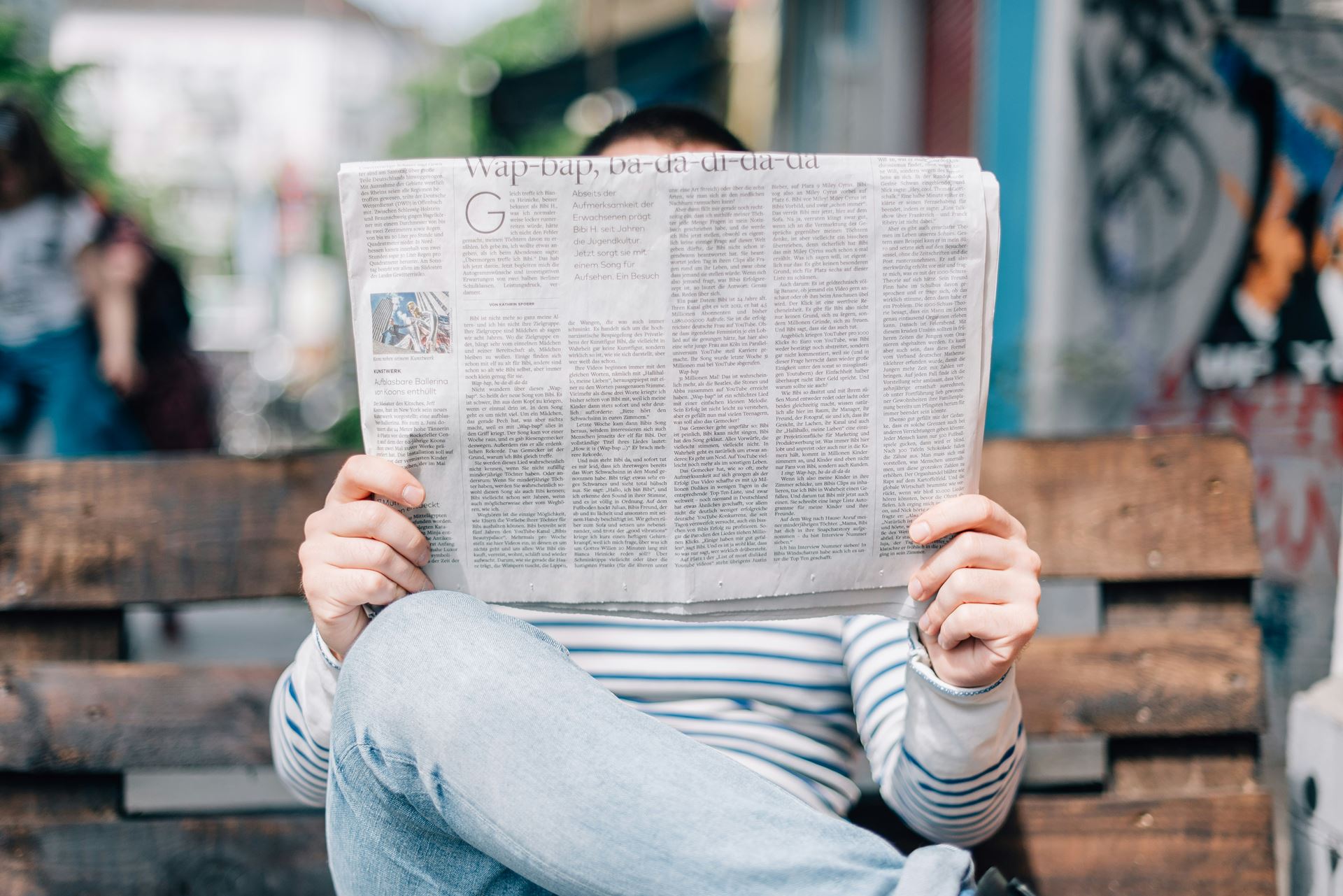 Man sat on bench reading a newspaper